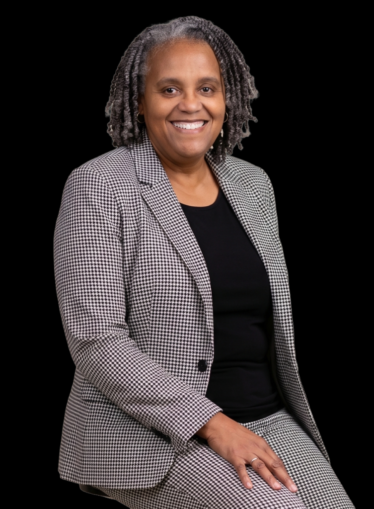 3/4 portrait of Myra Coffield wearing a black/white houndstooth print suit and a black top.